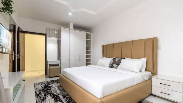 A modern bedroom with a large bed, a wardrobe, and a bedside table. - Luxury 4-Bedroom Duplex in Lekki with Snooker, Jacuzzi, Fast Wi-Fi & 24/7 Power (Lekki)