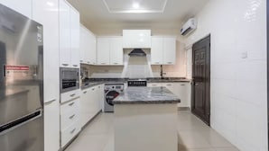 A modern kitchen with white cabinetry, stainless steel appliances, and a marble countertop. - Luxury 4-Bedroom Duplex in Lekki with Snooker, Jacuzzi, Fast Wi-Fi & 24/7 Power (Lekki)