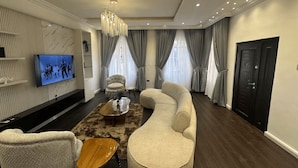 A modern living room with a sofa, armchairs, a coffee table, and a TV mounted on the wall. - Luxury 4-Bedroom Duplex in Lekki with Snooker, Jacuzzi, Fast Wi-Fi & 24/7 Power (Lekki)