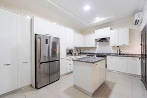 A modern kitchen with white cabinets, a stainless steel refrigerator, a stove, and a microwave. - Luxury 4-Bedroom Duplex in Lekki with Snooker, Jacuzzi, Fast Wi-Fi & 24/7 Power (Lekki)