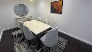 A modern dining room with a rectangular table, six chairs, a round mirror, and a contemporary painting. - Luxury 4-Bedroom Duplex in Lekki with Snooker, Jacuzzi, Fast Wi-Fi & 24/7 Power (Lekki)