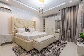 A modern bedroom with a large bed, bedside tables, a wardrobe, and a mirror. - Luxury 4-Bedroom Duplex in Lekki with Snooker, Jacuzzi, Fast Wi-Fi & 24/7 Power (Lekki)