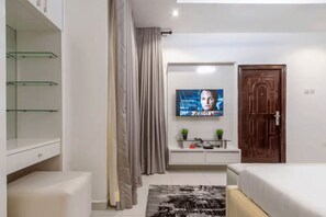 A bedroom with a TV, a wardrobe, a bedside table, and a bed. - Luxury 4-Bedroom Duplex in Lekki with Snooker, Jacuzzi, Fast Wi-Fi & 24/7 Power (Lekki)