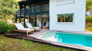 Uma casa moderna de dois andares com piscina, área de estar externa e varanda.