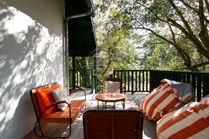 Eine Holzterrasse mit Gartenmöbeln, darunter eine Sitzecke mit Sofa und Stühlen sowie ein kleiner runder Tisch.