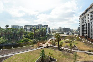 A modern building complex with a central courtyard, a water feature, and surrounding greenery. - Park Place | 1 Bed with Balcony and Lake Views (Cape Town)