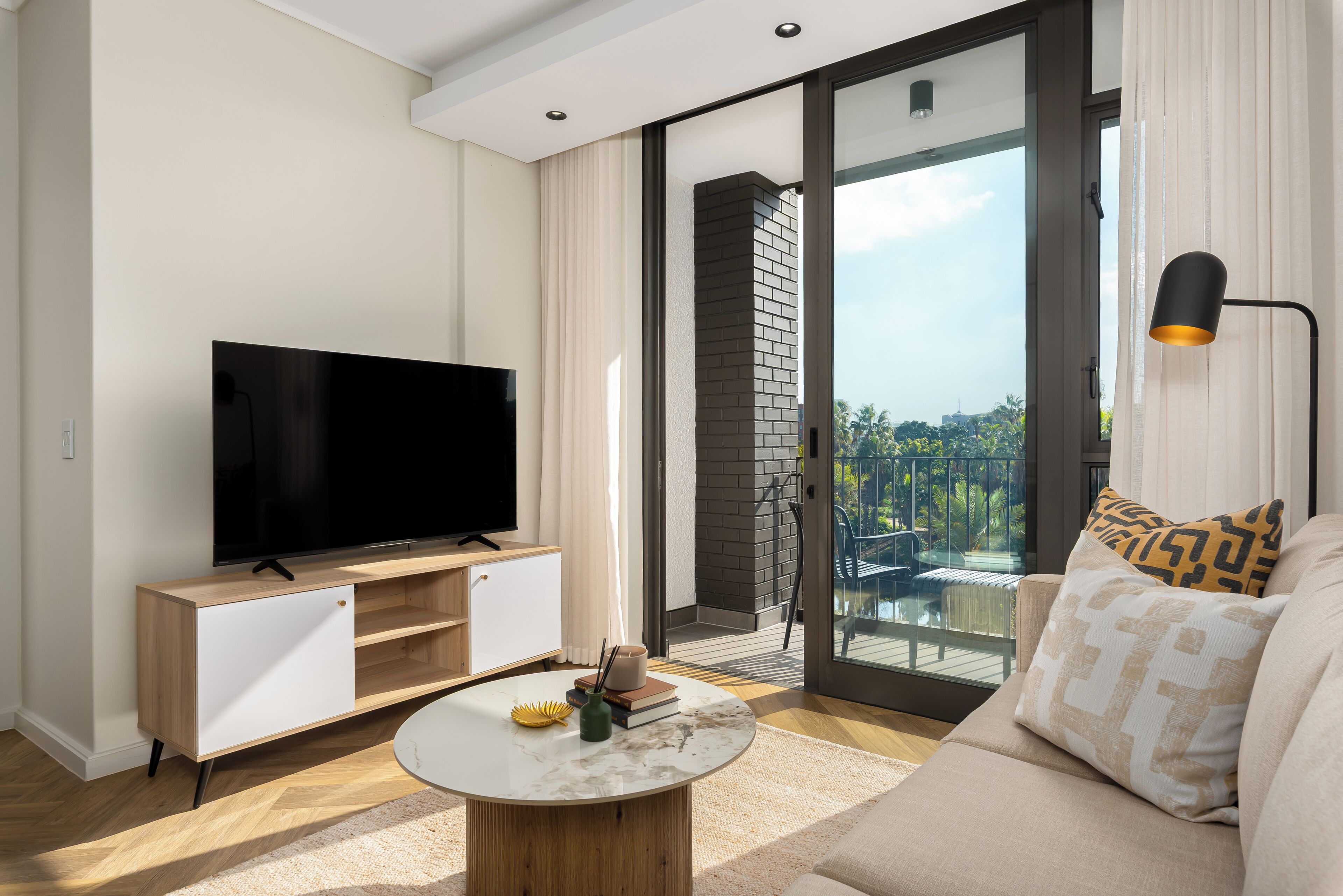 A modern living room with a flat-screen TV, a coffee table, and a sofa.