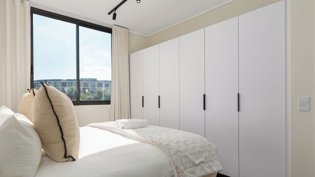 Ein Schlafzimmer mit einem großen Bett, einem Fenster mit Vorhängen und einem Schrank mit mehreren Türen.