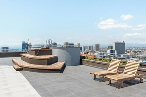 A rooftop terrace with wooden lounge chairs, a curved seating area, and a cityscape view. - FortyOnL | Table Mountain Retreat (Cape Town)