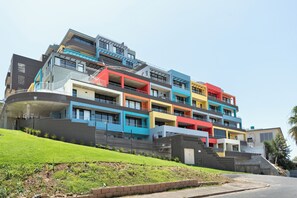 A multi-story residential building with balconies, a landscaped lawn, and a clear sky. - FortyOnL | Table Mountain Retreat (Cape Town)
