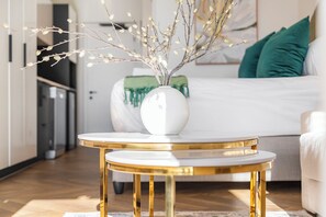 A modern living room with a white sofa, a round gold table, and a white vase with branches. - New Stylish Apartment | Table Mountain Views (Cape Town)