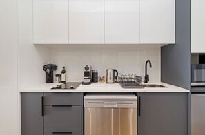 Eine moderne Küche mit Geschirrspüler, Wasserkocher und Kaffeemaschine auf der Arbeitsfläche.