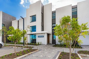 A modern building with a flat roof, large windows, and a sign reading 'CAMPHOR'. - New Stylish Apartment | Table Mountain Views (Cape Town)