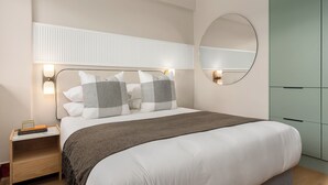 A bedroom with a bed, bedside lamps, a nightstand, a mirror, and a wardrobe. - Charlie and the Chairman | Elegant Urban Stay (Cape Town)