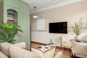 A living room with a sofa, a television, a bookshelf, and a plant. - Charlie and the Chairman | Elegant Urban Stay (Cape Town)
