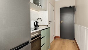 A compact kitchen with a built-in oven, a coffee machine, and a sink. - Charlie and the Chairman | Elegant Urban Stay (Cape Town)