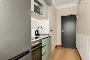 A compact kitchen with a built-in oven, a coffee machine, and a sink. - Charlie and the Chairman | Elegant Urban Stay (Cape Town)