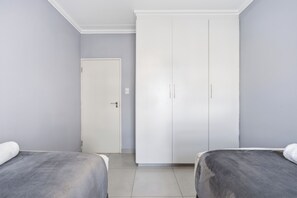 A room with two beds, a wardrobe, and a door.