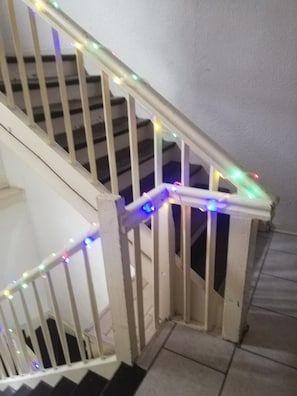 Una escalera de madera con barandilla y una guirnalda de luces multicolores.