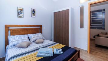 Quarto com cama, guarda-roupa, sofá e janela.