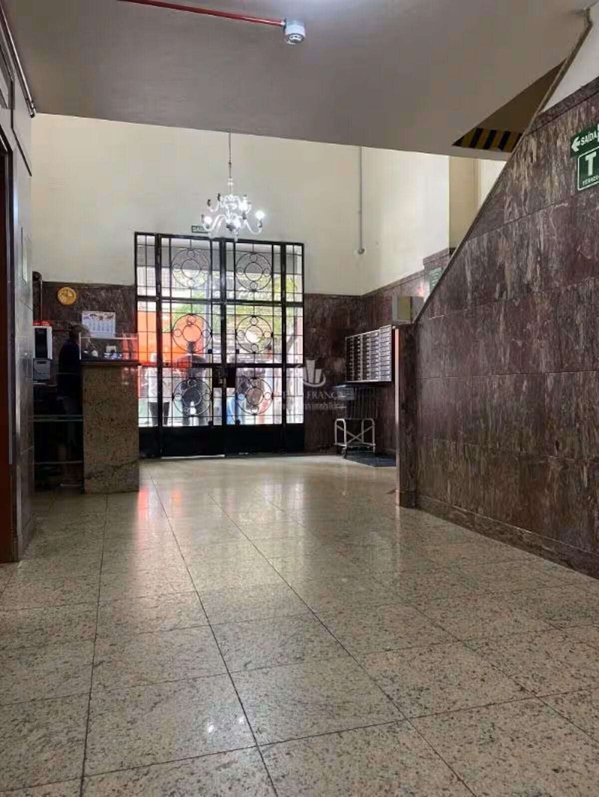 A lobby with a reception desk, a chandelier, and a tiled floor.