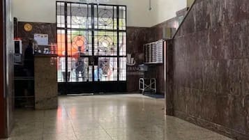 Um lobby com balcão de recepção, um candelabro e piso de azulejos.