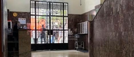 A lobby with a reception desk, a chandelier, and a tiled floor.