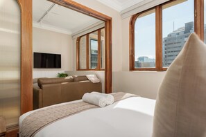 Ein Hotelzimmer mit Bett, einer Couch, einem Fernseher und einem Fenster mit Blick auf die Stadt.