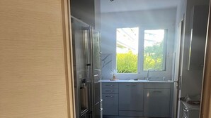 A narrow kitchen with a window, a refrigerator, and cabinets. - Luxury 3-Bedroom Apartment in Cannes Festival with Terrace (Cannes)
