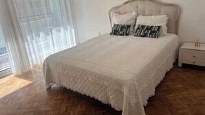 A bedroom with a large bed, a nightstand, and a window with blinds. - Luxury 3-Bedroom Apartment in Cannes Festival with Terrace (Cannes)