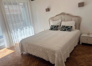 Ein Schlafzimmer mit einem großen Bett, einem Nachttisch und einem Fenster mit Jalousien.