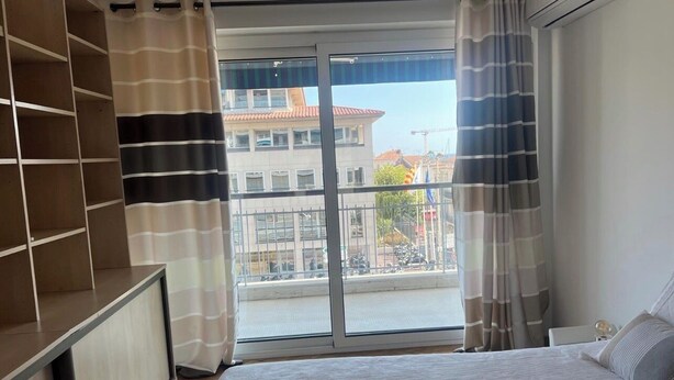 A bedroom with a bed, a wardrobe, and a large window with curtains. - Luxury 3-Bedroom Apartment in Cannes Festival with Terrace (Cannes)