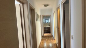 A hallway with wooden flooring leading to a kitchen area. - Luxury 3-Bedroom Apartment in Cannes Festival with Terrace (Cannes)