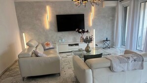 A modern living room with two sofas, a coffee table, a flat-screen TV mounted on the wall, and a marble floor. - Luxury 3-Bedroom Apartment in Cannes Festival with Terrace (Cannes)