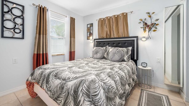 A bedroom with a bed, curtains, a wall clock, and a mirror. - 3 Min Walk to Beach | Private Triplex Retreat (Indian Rocks Beach)