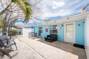 A building with a blue exterior, a covered patio area with outdoor seating, and a fire extinguisher mounted on the wall. - 3 Min Walk to Beach | Private Triplex Retreat (Indian Rocks Beach)