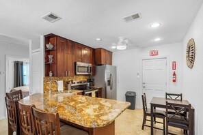 A modern kitchen with granite countertops, stainless steel appliances, and wooden cabinets. - 3 Min Walk to Beach | Private Triplex Retreat (Indian Rocks Beach)