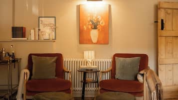 Una habitación acogedora con dos sillones, una mesita, un radiador y un armario de madera.