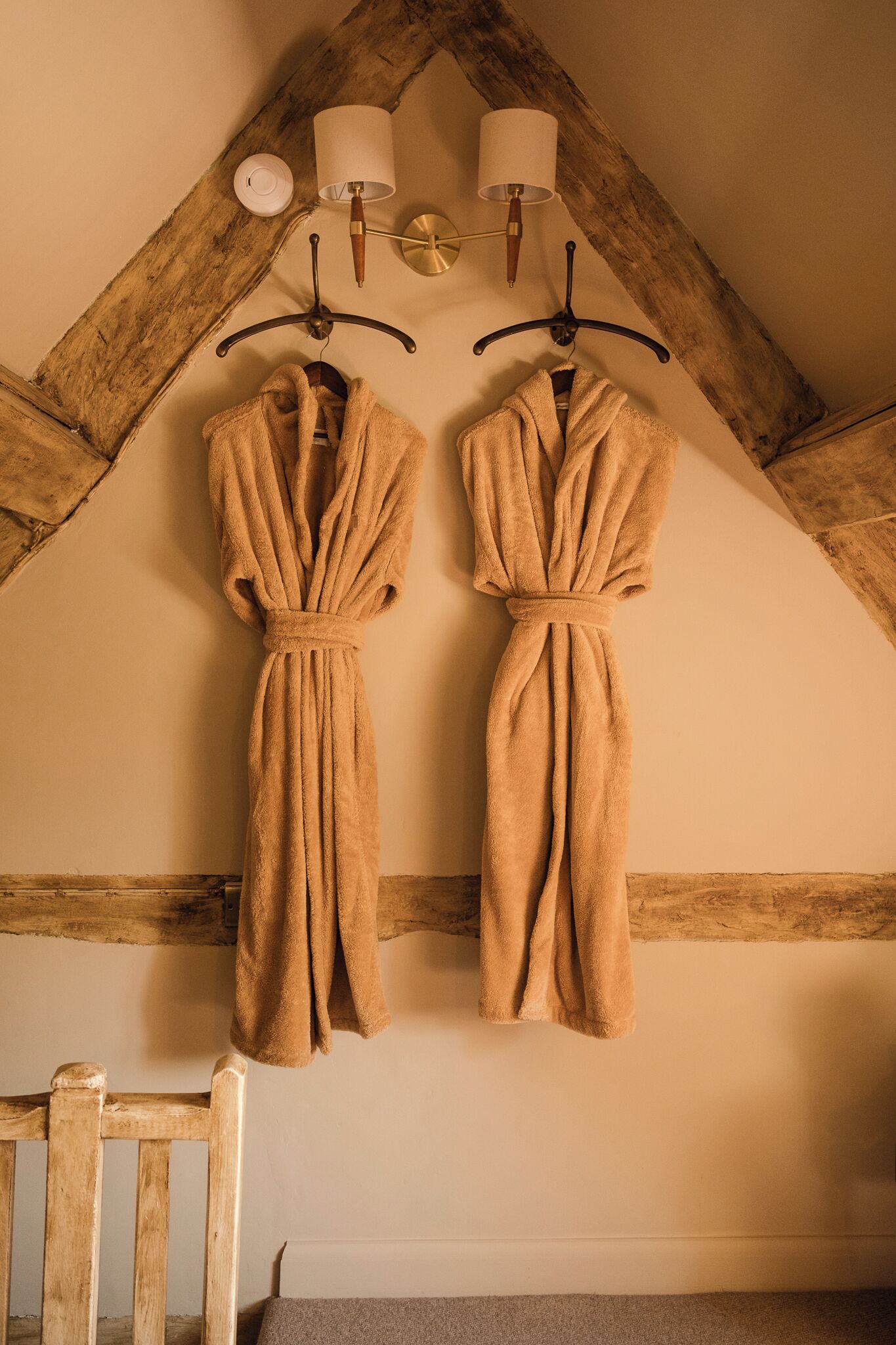 Two towels hanging on hooks in a room with wooden beams on the ceiling.
