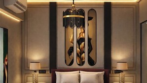 Un dormitorio moderno con una cama redonda, una gran obra de arte en la pared y una lámpara colgante original.