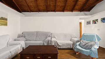 Ein Wohnzimmer mit Holzboden, einer Couch, einem Sessel und einem Couchtisch.