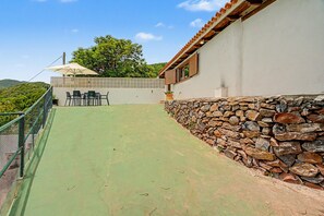 A patio area with a table and chairs, a stone wall, and a view of the surrounding landscape. - Holiday Home 'Los Brezos' with Mountain Views, Private Terrace and Wi-Fi (Agulo)