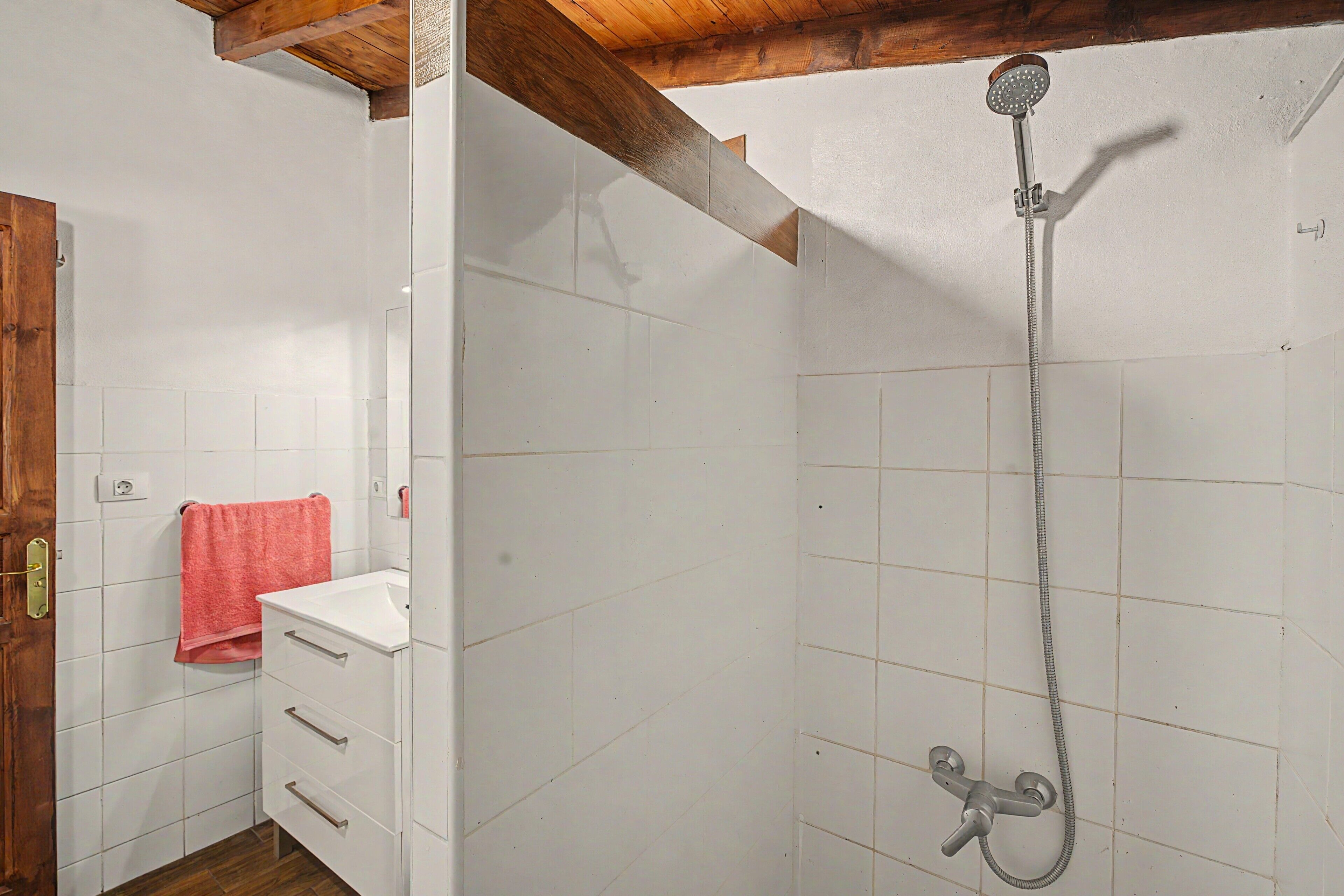 A bathroom with a shower, a sink, and a wooden door.