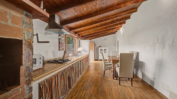 Una cocina con techo de madera, pared de ladrillo y suelo de baldosas.