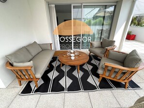 A patio area with a sofa set, two chairs, a round table, and a patterned rug. - Appt Brémontier 2 - Hossegor center - Terrace (Soorts-Hossegor)