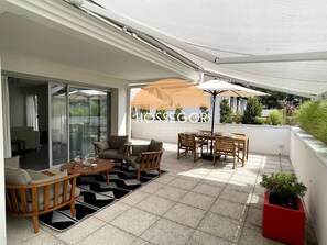 A covered outdoor seating area with a table and chairs, a sofa, and a potted plant. - Appt Brémontier 2 - Hossegor center - Terrace (Soorts-Hossegor)
