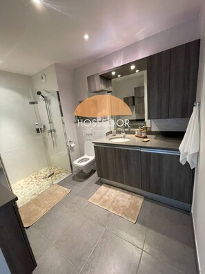 Ein modernes Badezimmer mit einer in Glas eingefassten Dusche, einer Toilette und einem Waschtisch mit Spiegel.