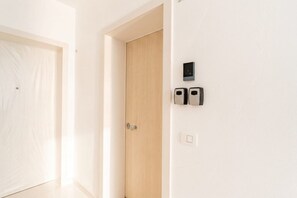 Ein Zimmer mit Holztür, weißer Wand und einem wandmontierten Gegensprechanlage.