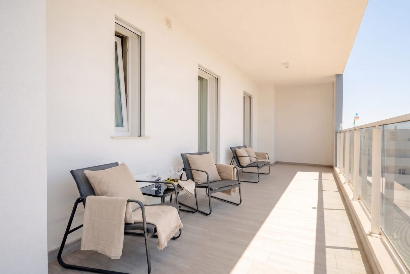 Un balcone con quattro sedie e un tavolo, ognuno dotato di un cuscino.