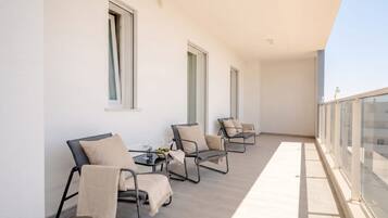Un balcone con quattro sedie e un tavolo, ognuno dotato di un cuscino.